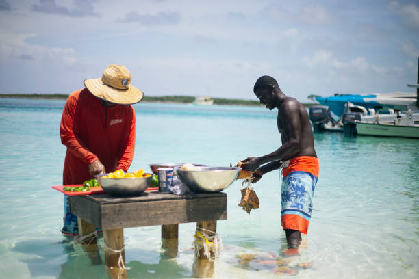 deux des bahamas local/native préparation conque pour la salade de conque sur un stand dans l’eau - swimwear caribbean sea beach water photos et images de collection