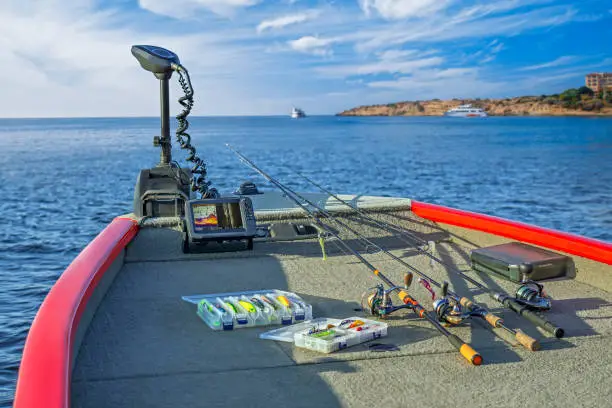 Photo of Fishing tackle set and fishfinder, echolot, sonar at the boat. Spinning rods with reels and lures