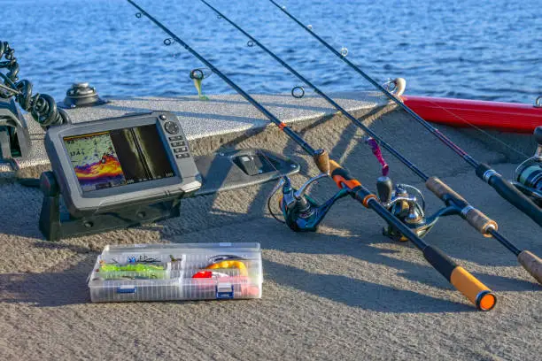 Photo of Fishing tackle set and fishfinder, echolot, sonar at the boat. Spinning rods with reels and lures