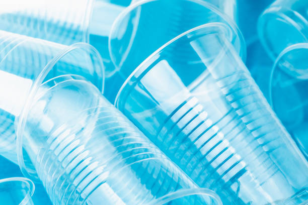 New clean empty transparent disposable plastic glasses on bright blue background, close up