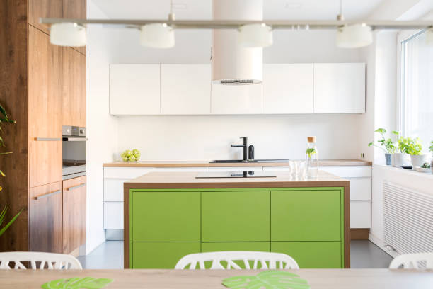 istock Modern and design scandinavian space with kitchen island, table and accessories. Sunny and bright kitchen with white white wall. Stylish accessories. 1001153890