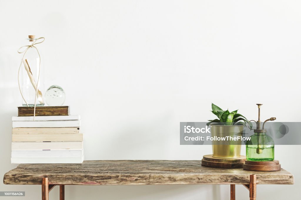 Stylish and modern decor with wooden console, books, plants and accessories. Copy space for inscription. Modern and stylish concept of wooden consol and mock up framer. Table Stock Photo