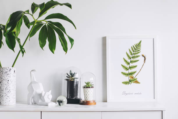 istock Creative cupboard with mock up poster frame, cat figure, tropical leaf and plants in glass garden. Modern scandinavian interior. 1001156670