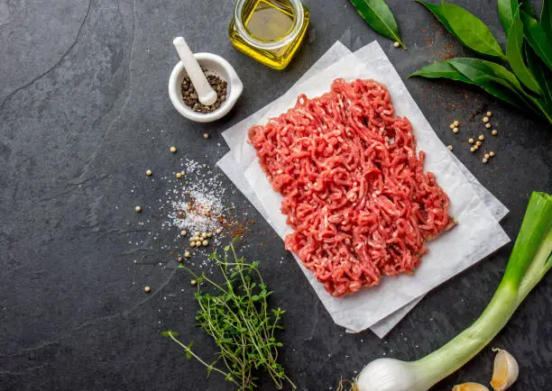 Mince. Ground meat with ingredients for cooking on black background. Minced beef meat. Top view.