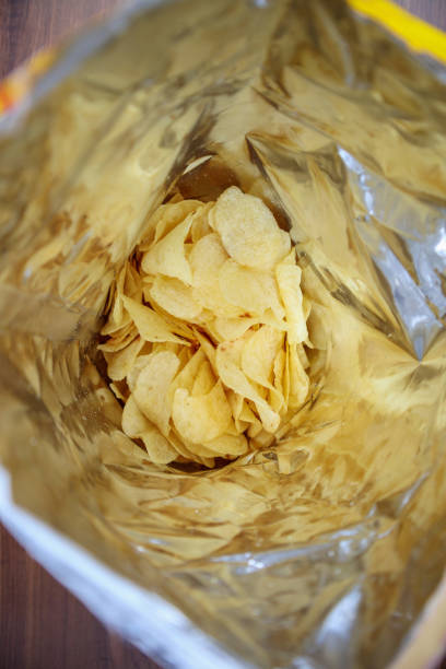 istock Potato chips in open snack bag close up on table floor 1001168002