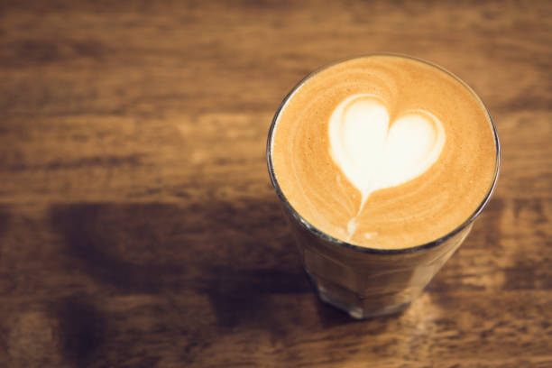Beautiful heart shape latte art coffee in the glass on wood table with copy space