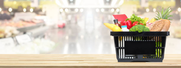 shopping basket full of food and groceries on the table in supermarket - shopping basket imagens e fotografias de stock