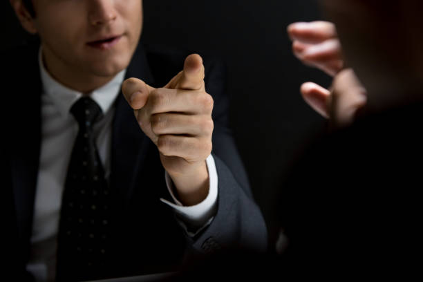 Angry official pointing hand to suspect and asking questions Angry official pointing hand to suspect and asking questions in dark private room - investigation and interrogation concepts Threats stock pictures, royalty-free photos & images