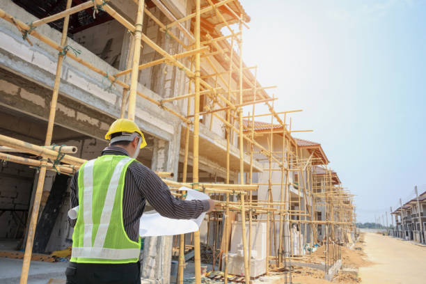 istock Professional engineer architect worker with protective helmet and blueprints paper at house building construction site 1001168356
