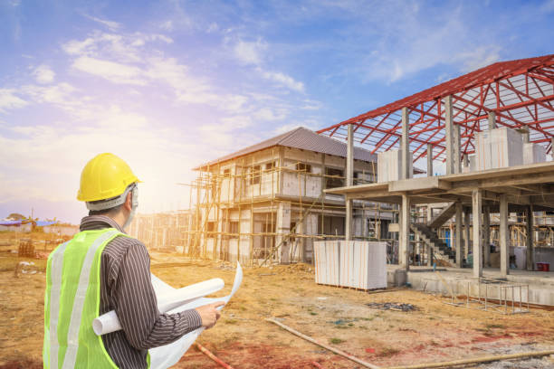 istock Professional engineer architect worker with protective helmet and blueprints paper at house building construction site 1001168362