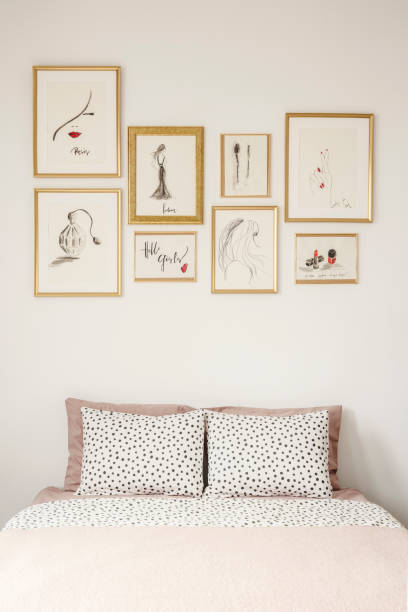istock Stylish drawings gallery in golden frames above a cozy double bed with polka dot sheets in a white apartment room interior of a beauty lover 1001171308
