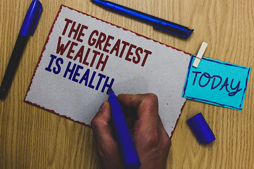 Conceptual hand writing showing The Greatest Wealth Is Health. Business photo text being in good health is the prize Take care Man holding marker paper clothespin express ideas wooden table