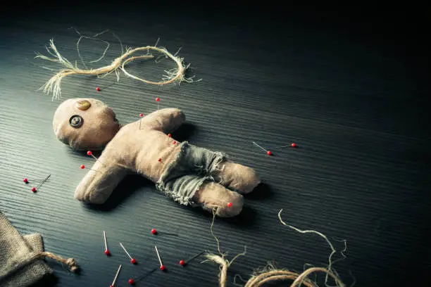 Voodoo Doll on a wooden background with dramatic lighting