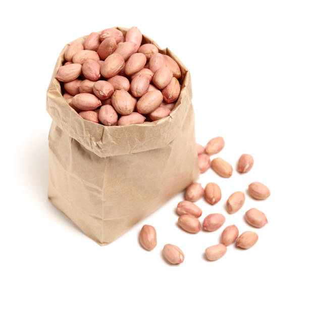 istock Peeled peanuts scattered from a wooden bowl on white background 1001193132