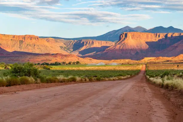 Wide dirt road through Utah desert with beautiful views of red rock mesas