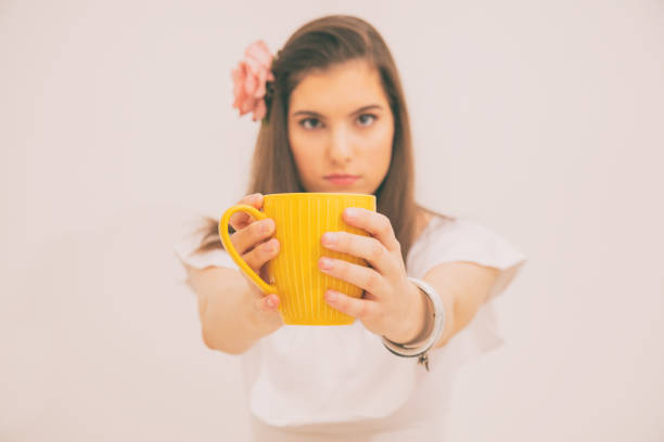 istock Girl holding tea/coffee cup and looking at camera. Focus on cup. 1001273682