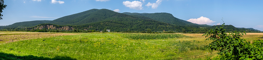 Panoramic view of the wild green field at the foot of the gentle mountain ranges