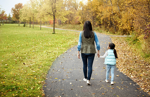 Rearview shot of a mother and her little daughter enjoying a walk outdoors