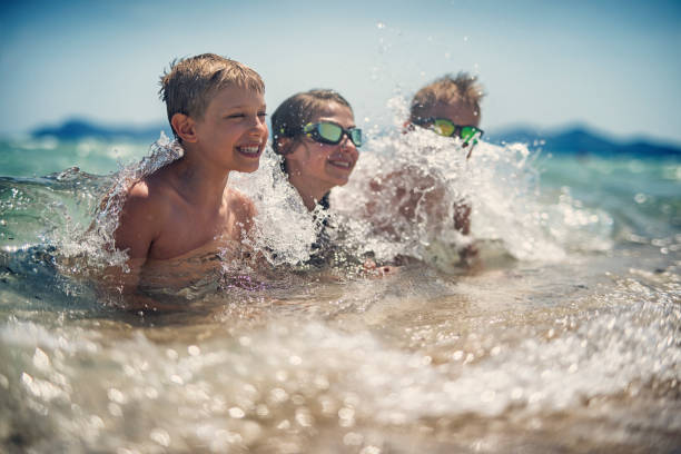 niños jugando en las olas del mar - spraying beaches summer sunlight fotografías e imágenes de stock