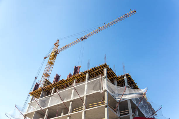 istock concrete modern building and tower crane against blue sky background 1001291978