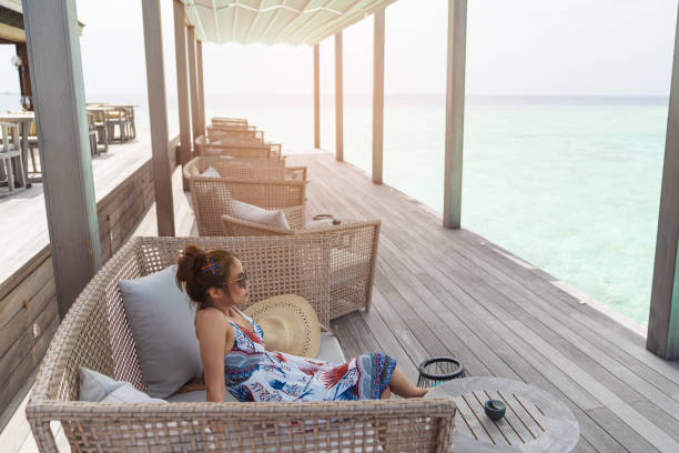Asian beautiful woman enjoyful on sofa, vacation holiday concepts with tropical Maldives island background.