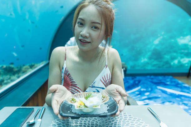istock Asian beautiful woman dinner on undersea world. 1001295498