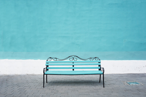 Blue bench on a background of blue wall. Front view, empty space.