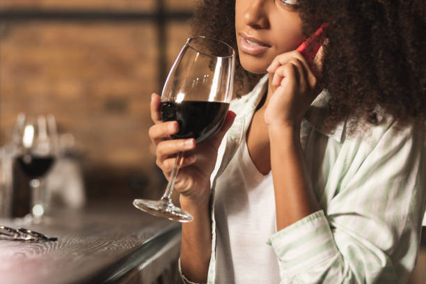 istock Elegant young woman talking on phone and drinking wine 1001302518