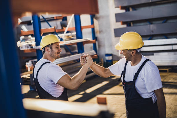 istock Happy manual workers greeting each other in aluminum mill. 1001305082
