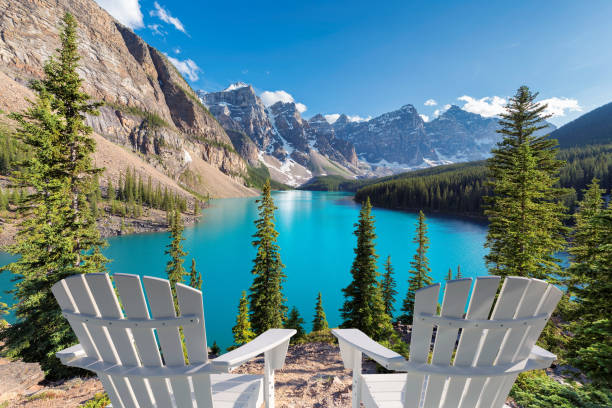 Canadian Rockies Two chairs near beautiful turquoise waters of the Moraine Lake at sunset with snow-covered peaks above it in Rocky Mountains, Banff National Park, Canada. canadian rockies stock pictures, royalty-free photos & images