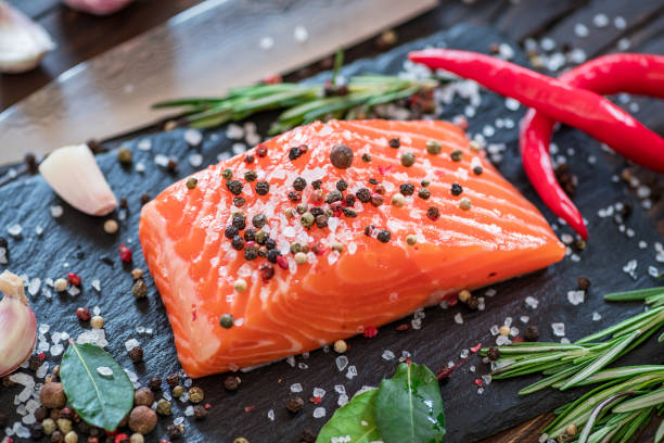 istock Fresh salmon fillets on black cutting board with herbs and spices. 1001320886
