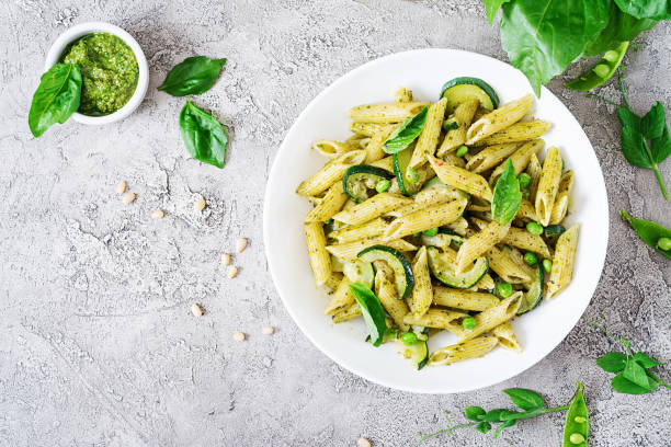 penne pasta con salsa de pesto, calabacín, guisantes y albahaca. comida italiana. vista superior. la endecha plana. - penne fotografías e imágenes de stock