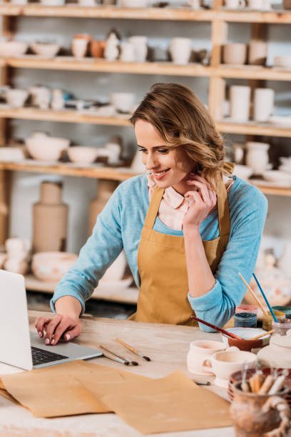 istock beautiful female potter using laptop in workshop with ceramics 1001334990