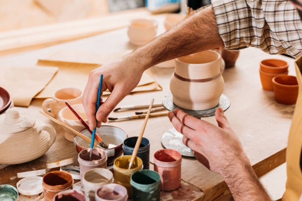 istock cropped view of male potter painting ceramic dishware in workshop 1001338310