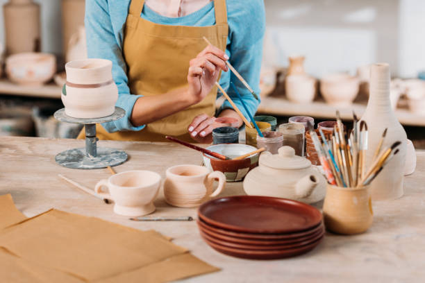 istock cropped view of potter in apron painting ceramic dishware in workshop 1001339012