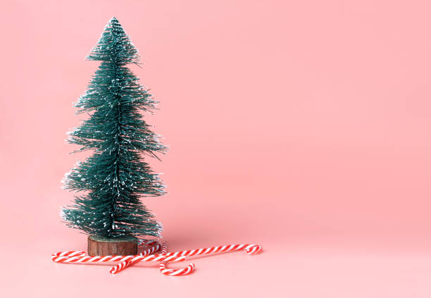 istock Christmas tree with candy cane on pastel pink studio background.Holiday festive celebration greeting card with copy space 1001341702