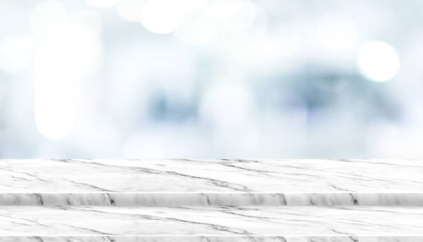 istock Empty step white marble table top with blur patient waiting for doctor at hospital with bokeh light at background,Mock up template for display of your design,Banner for advertise of product. 1001341788