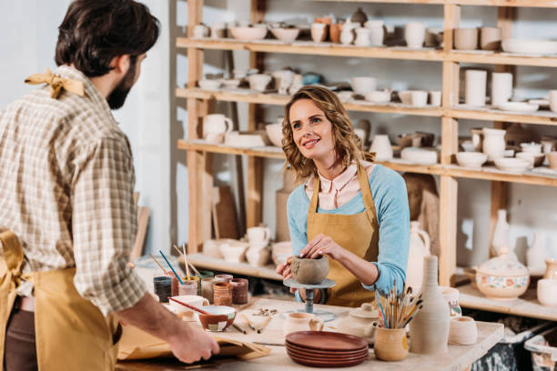 istock man with papers and female potter with ceramics in workshop 1001345442