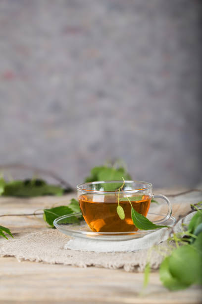 istock Birch leaf train a glass cup on a wooden surface. 1001345740