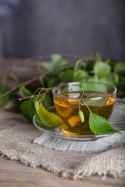 istock Birch leaf train a glass cup on a wooden surface. 1001345774