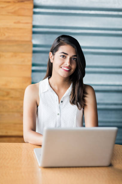 istock Beautiful young woman using laptop and smiling at the camera 1001345844
