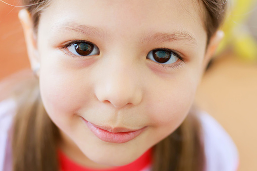 Adorable little girl with big brown eyes, indoor portrait.