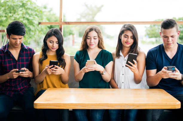 istock Group of young people sitting and using mobile phones 1001353176