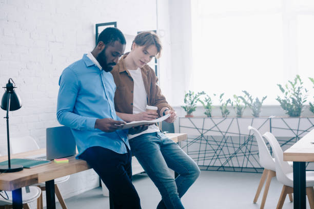 istock stylish businessmen talking and watching on textbook in modern office 1001354210