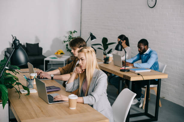 istock multicultural business coworkers sitting at table and working on laptops in modern office 1001354258