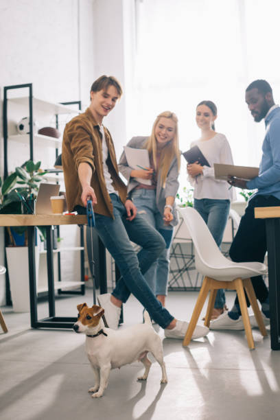 istock smiling multiethnic business colleagues with textbooks and jack russel terrier on leash in modern office 1001354300