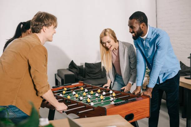 istock smiling multiethnic business colleagues playing table football in modern office 1001354500