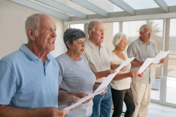 Shot of a group of senior people singing from sheets together in a retirement home