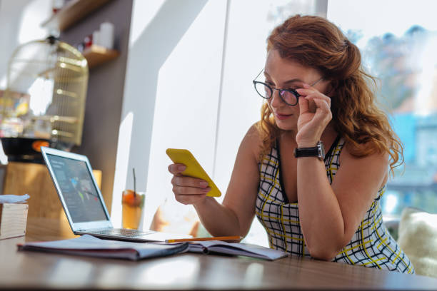 istock Red-haired woman with wavy hair reading message on her phone 1001358024