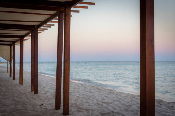 istock Wooden shelter, awning, beach and water's edge at sunset 1001359156